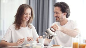 A man pouring coffee for a woman while sharing a relaxed breakfast together