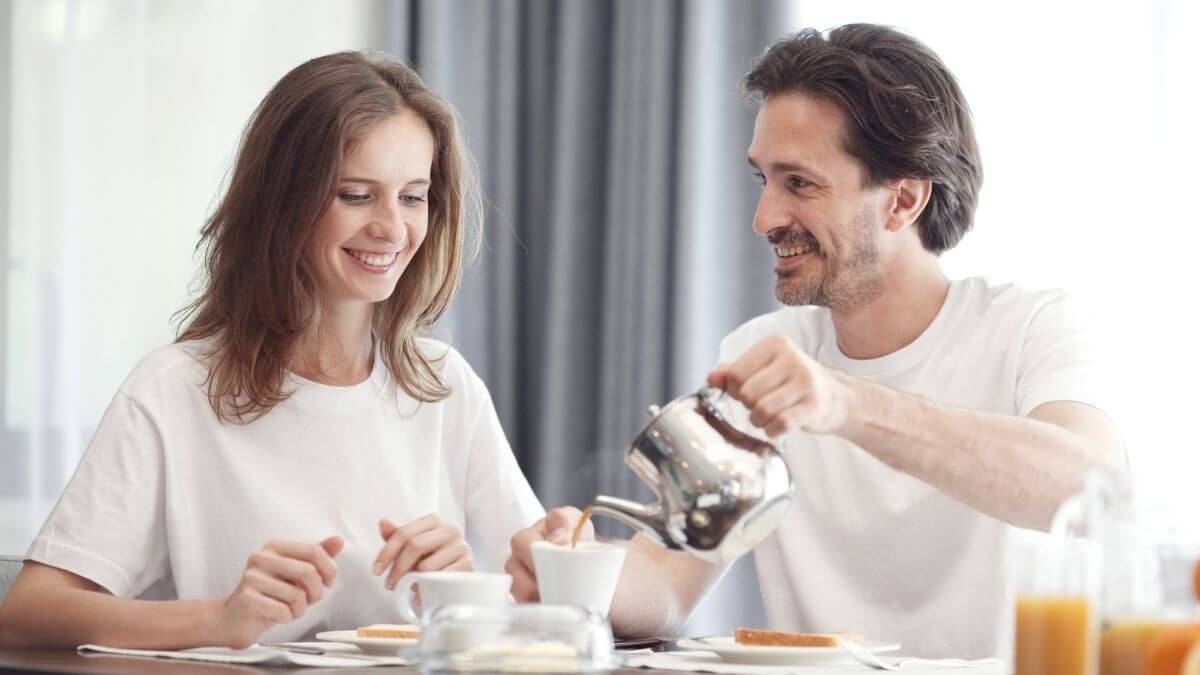 A man pouring coffee for a woman while sharing a relaxed breakfast together